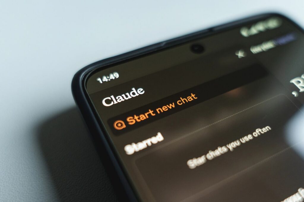 A smartphone screen displays a chat app with the name Claude at the top and an option to Start new chat highlighted in orange. The time shown is 14:49.